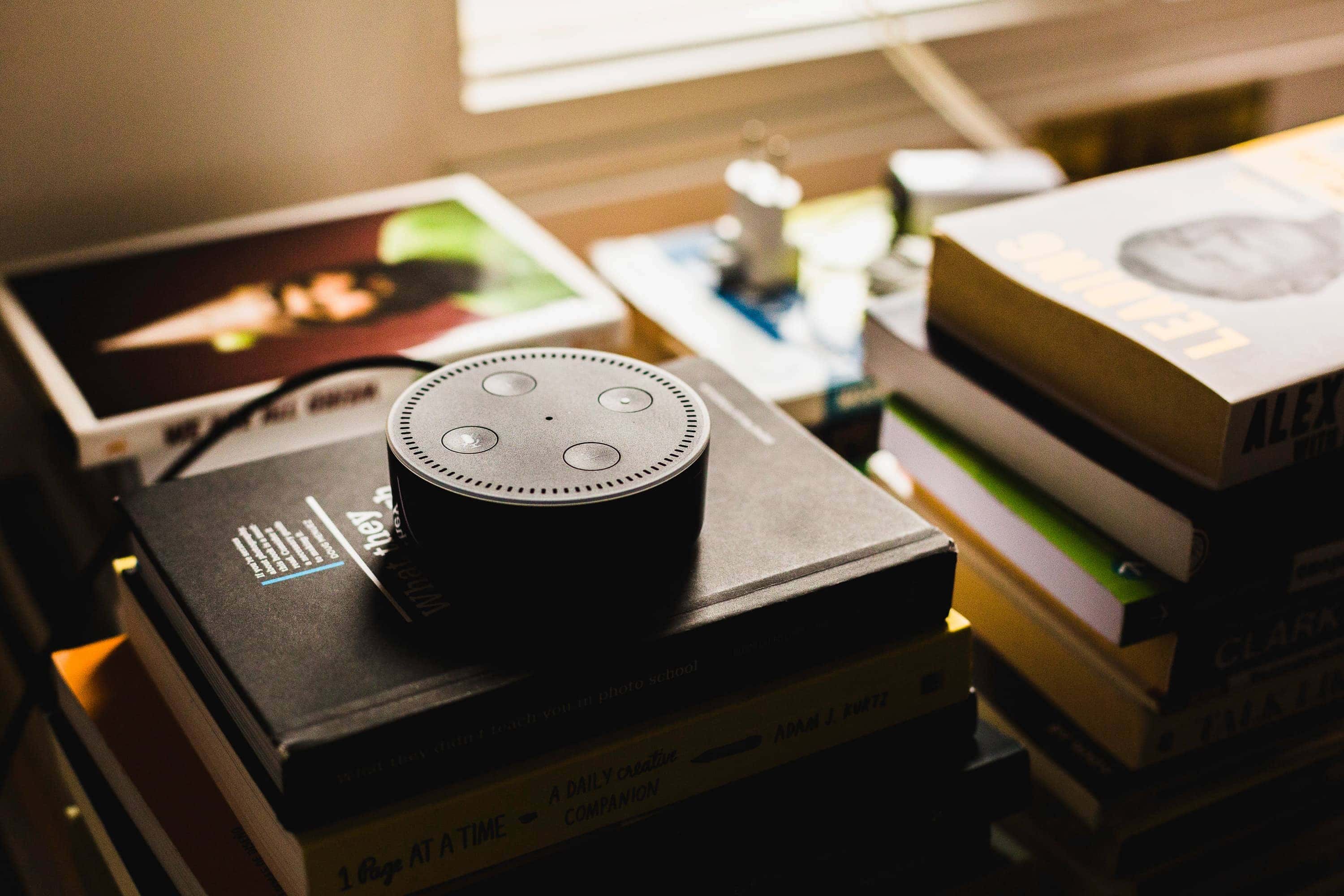 Alexa AI assistant sitting on top of a pile of books